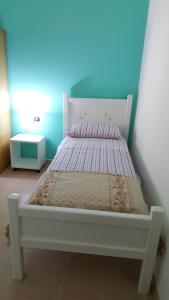 een slaapkamer met een wit bed en een blauwe muur bij Casa con ampio giardino Sulcis in Giba