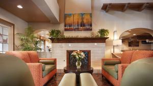 a lobby with a fireplace and orange chairs and a table at Best Western San Dimas Hotel & Suites in San Dimas