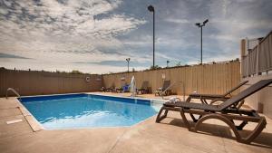 einen Pool mit einer Bank und einem Zaun in der Unterkunft Best Western Crossroads Inn in Schererville
