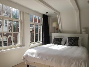 a white bedroom with a bed and two windows at Nine Streets Inn in Amsterdam