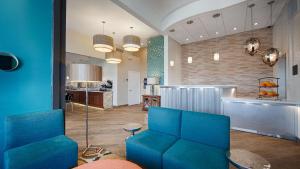 a living room with blue chairs and a kitchen at Best Western The Oasis at Joplin in Joplin