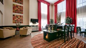 a living room with red curtains and a table and chairs at Best Western Plus Cushing Inn & Suites in Cushing
