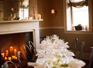 a dining room with a table with glasses and a fireplace at Zero George Hotel in Charleston