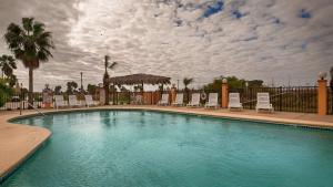 a large swimming pool with chairs and a fence at Best Western Padre Island in Corpus Christi