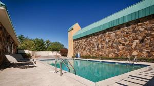 a swimming pool next to a building with a stone wall at Best Western Newport Inn in Newport