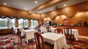 a restaurant with tables and chairs and a kitchen at Best Western Casa Villa Suites in Harlingen