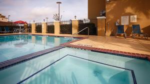 a large swimming pool with two chairs and a building at Best Western Plus Katy Inn & Suites in Katy