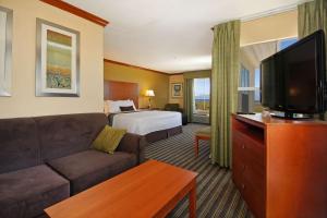 a hotel room with a couch and a bed and a television at Best Western Plus Seawall Inn & Suites by the Beach in Galveston