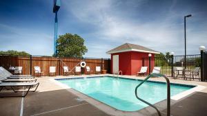 a swimming pool with chairs and a red building at Best Western Plus Waco North in Waco