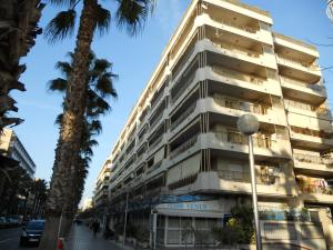 a tall white building on a street with a palm tree at Apartamentos Indasol in Salou