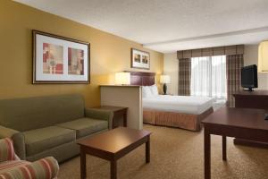 a hotel room with a bed and a living room at Country Inn & Suites by Radisson, Atlanta Airport South, GA in Atlanta