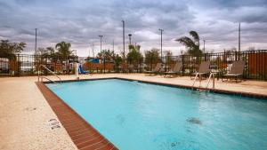a large swimming pool with chairs and a fence at Best Western Plus New Orleans Airport Hotel in Kenner