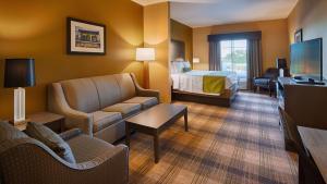 a hotel room with a bed and a living room at Best Western Plus New Orleans Airport Hotel in Kenner