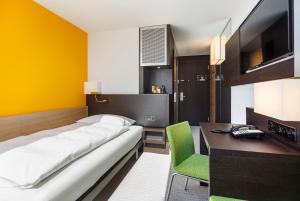 a bedroom with a bed and a desk and a television at Züri by Fassbind in Zürich