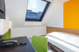 a bedroom with a bed and a desk with a phone at Züri by Fassbind in Zurich