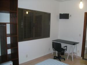 een slaapkamer met een bureau, een raam en een bureau bij Pousada Jaó in Goiânia