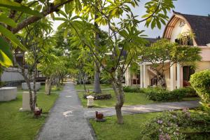 a path through a garden with trees and a building at Vila Ombak in Gili Trawangan