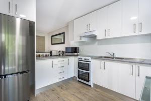a kitchen with white cabinets and a stainless steel refrigerator at Hamilton on Beaumont in Newcastle
