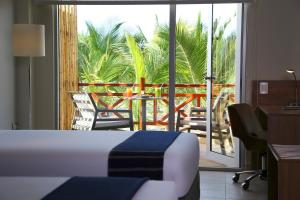 a hotel room with a bed and a desk and a balcony at Casa Andina Select Zorritos Tumbes in Zorritos