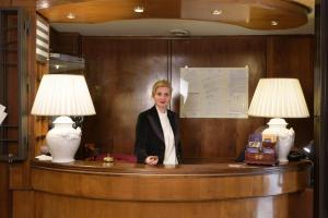 
a woman standing in front of a wooden desk at Hotel Morchio in Diano Marina
