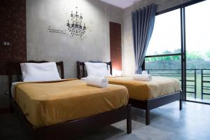 2 Betten in einem Zimmer mit einem großen Fenster in der Unterkunft The Boat House in Ranong