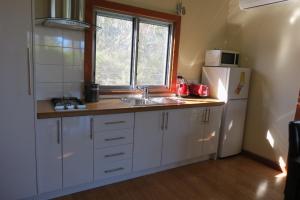 a kitchen with a sink and a white refrigerator at Butterworth Cottage in Castlemaine