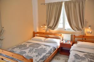 two beds in a small room with a window at Hotel Germany in Paralia Katerinis