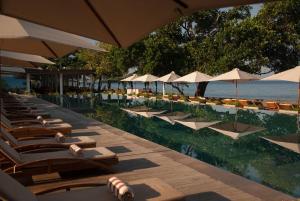 a row of lounge chairs and umbrellas on the beach at Living Asia Resort and Spa in Senggigi