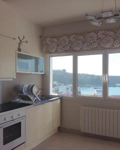 a kitchen with two large windows with a view of the water at Apartamento Bellavista in Luarca +13 photos