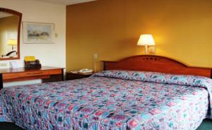 une chambre d'hôtel avec un lit et un bureau avec une lampe dans l'établissement Speedway Inn, à Bristol