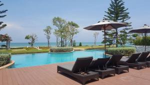 une piscine avec des chaises et un parasol dans l'établissement Tascany Sea Beach Chaam-Huahin, à Cha Am