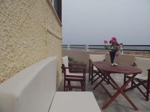 a table and chairs on a balcony with a vase of flowers at Gianna's House in Stavros