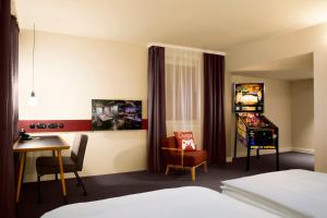 a room with a bed, chair and a tv at Pentahotel Prague in Prague
