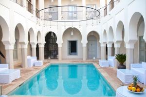 an indoor pool in a building with white furniture at Riad Nashira & Spa in Marrakech