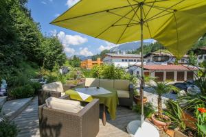 a patio with a table and a yellow umbrella at Hotel Metzgerwirt in Fieberbrunn
