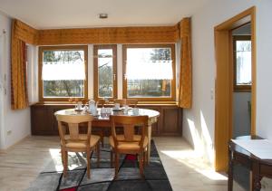 a dining room with a table and chairs and windows at Ferienhaus Bauerngarten in Bad Buchau