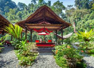 un pabellón con un banco rojo en un jardín en EcoTravel Cottages Bukit Lawang en Bukit Lawang