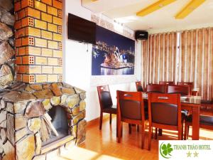 a restaurant with a stone fireplace and a table and chairs at Thanh Thao Dalat Hotel in Da Lat