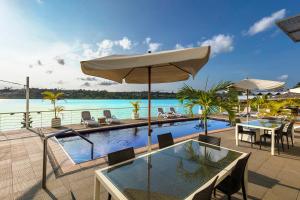 einen Pool mit einem Tisch, Stühlen und einem Sonnenschirm in der Unterkunft Chantillys on the Bay in Port Vila