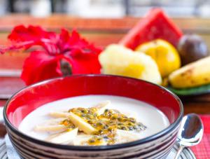 a red bowl of soup with fruit in the background at EcoTravel Cottages Bukit Lawang in Bukit Lawang