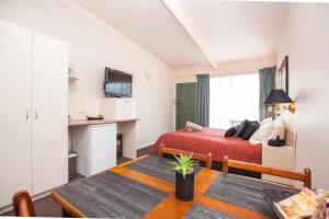 Habitación pequeña con cama y mesa con sidra de mesa en Mid City Motel, en Mount Gambier