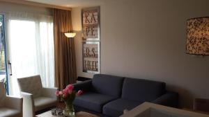 un soggiorno con un divano blu e una finestra di De Kapershut a Hollum