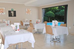 a dining room with white tables and chairs and a large window at 6 on Morris Guest Lodge in Johannesburg