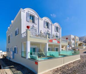 a white building with people sitting on the balcony at Ellinon Thea Boutique Hotel in Firostefani