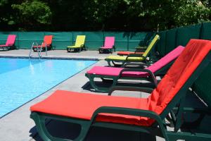 a row of colorful lounge chairs next to a swimming pool at Logis Le Ceans in Orpierre
