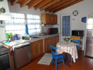 リベイラ・グランデにあるVila Lauraのキッチン(木製キャビネット、テーブル、青い椅子付)