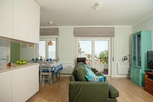 エリセイラにあるEriceira Atlantic Ocean Hill Apartmentのリビングルーム(緑のソファ付)、キッチンが備わります。