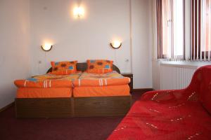 a bedroom with a bed with orange sheets and a chair at Aseva House Family Hotel in Bansko