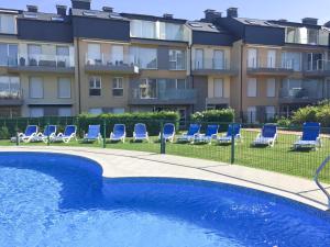 basen z niebieskimi krzesłami i budynek w obiekcie Apartamento Premium Playa Altar 2 w mieście Barreiros