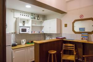 Eine Küche mit weißen Schränken und einer Theke mit Hockern in der Unterkunft Tempi Hotel in Athen